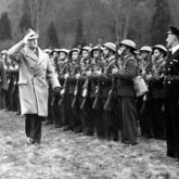 Primeiro-Ministro da República da Polônia e Comandante-em-Chefe, General Władysław Sikorski (de casaco claro, fazendo uma saudação) acompanhado pelo, entre outros, Ministro da Defesa Nacional, General Marian Kukiel, passa à frente da guarda de honra do Exército Polonês (Grã-Bretanha, 1940-43). Fonte: Arquivo Digital Nacional